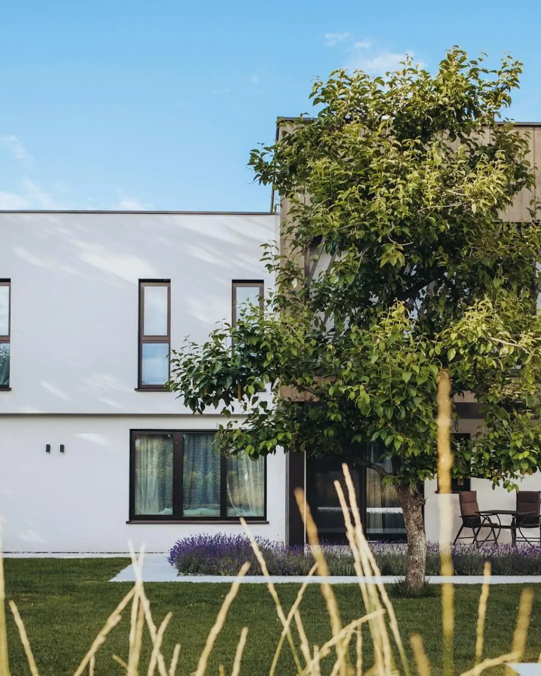 Facciata bianca di una casa Nathea con giardino e albero